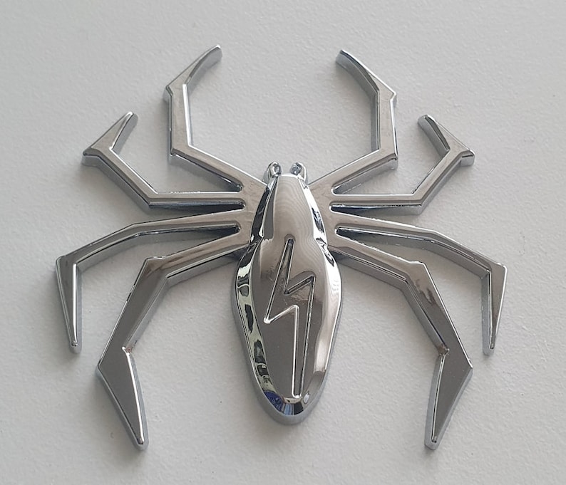 May include: A chrome-plated spider with a lightning bolt design on its body. The spider has eight legs and is a decorative item.