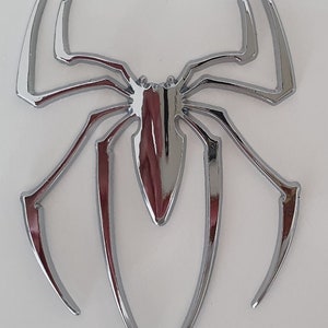Pode incluir: Um design de aranha cromado, um emblema decorativo com um acabamento brilhante.