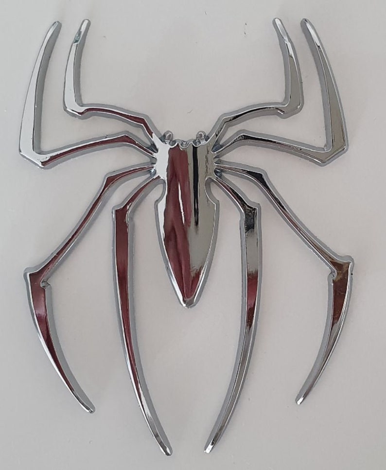 Pode incluir: Um design de aranha cromado, um emblema decorativo com um acabamento brilhante.