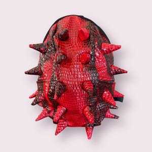 May include: Red and black spiky backpack with a crocodile-embossed design.
