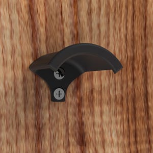 May include: Black metal bottle opener mounted on a wooden surface. The opener has a curved shape and two screws.