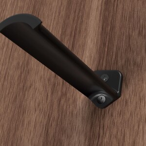 May include: Black metal shelf bracket with a curved design. The bracket is mounted to a wood surface with two screws.