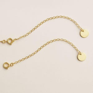 Può includere: Due prolunghe per collana color oro con un delicato design a catena. Ogni prolunga presenta un piccolo disco rotondo a un'estremità e una chiusura all'altra. Le prolunghe sono progettate per allungare le collane.