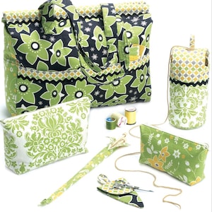 Può includere: Un set di accessori per cucito con un motivo floreale verde su sfondo nero. Include una borsa tote, pochette e un astuccio per aghi. Sono visibili anche rocchetti di filo e forbici.
