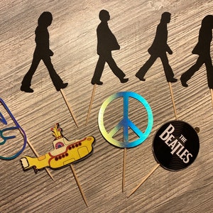 Set de 12 adornos para cupcakes con el símbolo de la paz de los Beatles para fiestas de cumpleaños de los años 70
