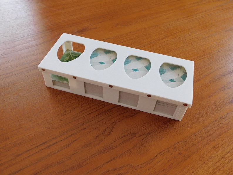 以下が含まれることがあります： 5つの区画があり、各区画に透明な窓が付いた白いプラスチック製の収納ボックス。窓には緑と白の葉の模様が見える。