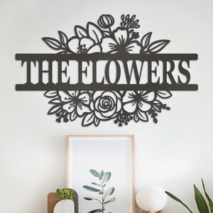 May include: Black metal wall decor with a floral design and the text "THE FLOWERS" in a bold font.