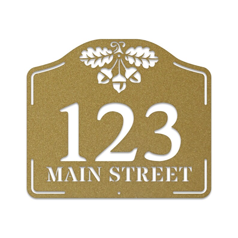 May include: Gold metal house number sign with an oak leaf and acorn design. The sign has the number 123 and the text "MAIN STREET" in white.