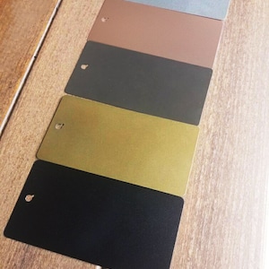 May include: Five small rectangular samples of different coloured paint. The colours are light blue, brown, dark grey, gold, and black.