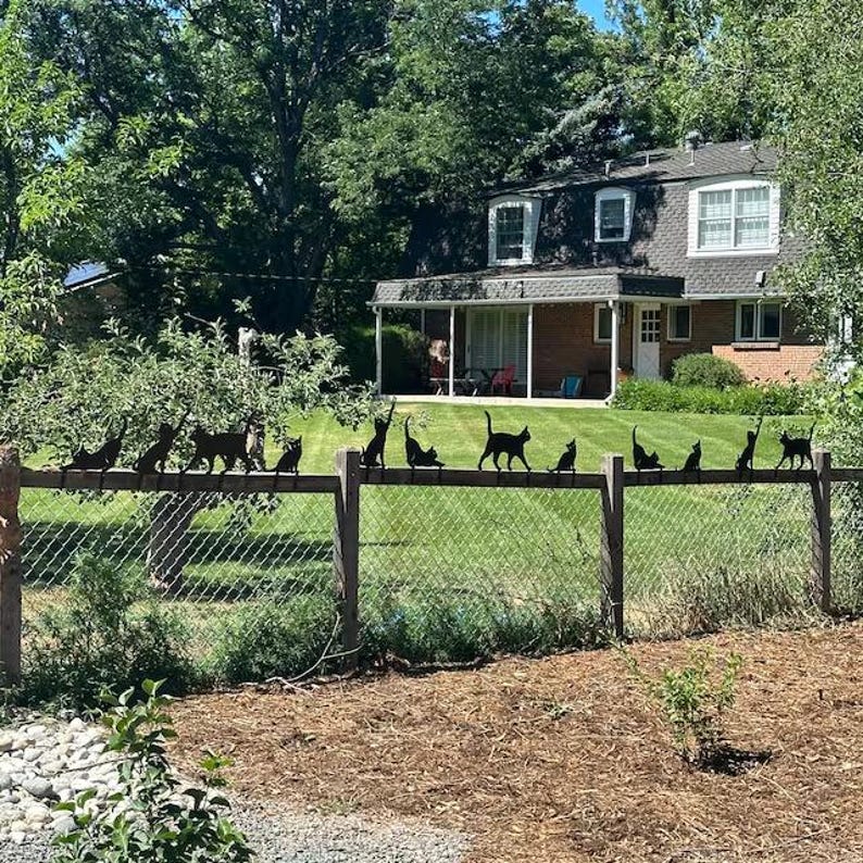 a group of cats on a fence in front of a house