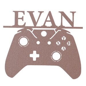 Pode incluir: Um recorte de madeira marrom de um controlador de videogame com o nome "EVAN" acima.