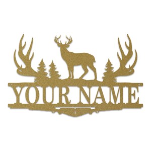 May include: Gold metal deer silhouette with antlers, two pine trees, and the text "YOUR NAME" on a gold metal background.