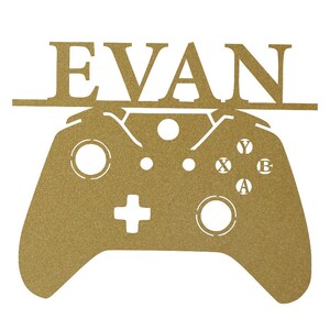 Pode incluir: Corte de metal dourado de um controlador de videogame com o nome "EVAN" acima.