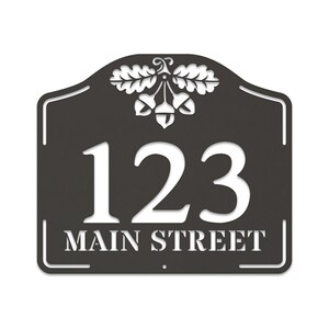 May include: Black metal house number sign with white lettering. The sign features the number 123 and the street name "MAIN STREET" with an acorn and oak leaf design at the top.