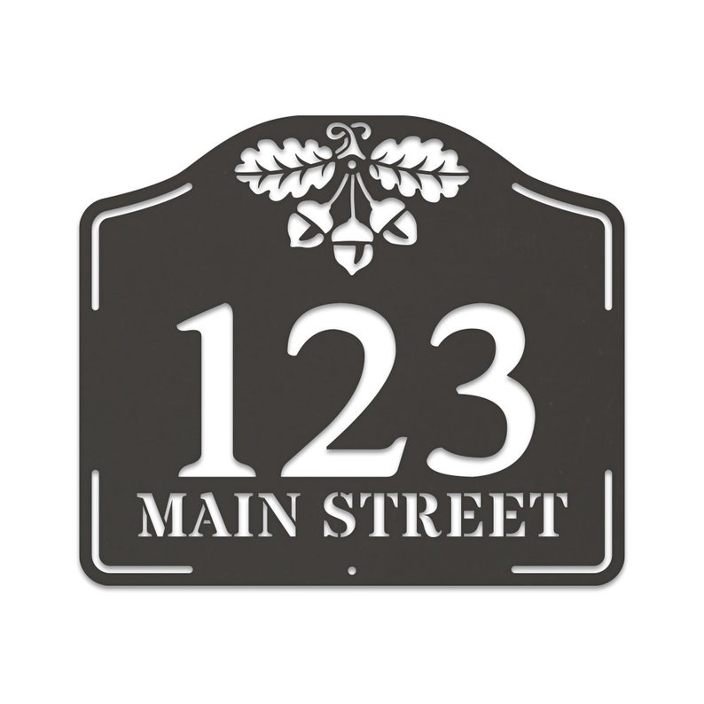 May include: Black metal house number sign with white lettering. The sign features the number 123 and the street name "MAIN STREET" with an acorn and oak leaf design at the top.
