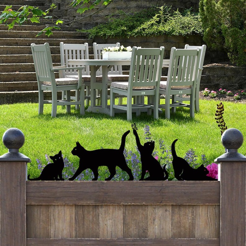 a group of cats sitting on top of a lush green field