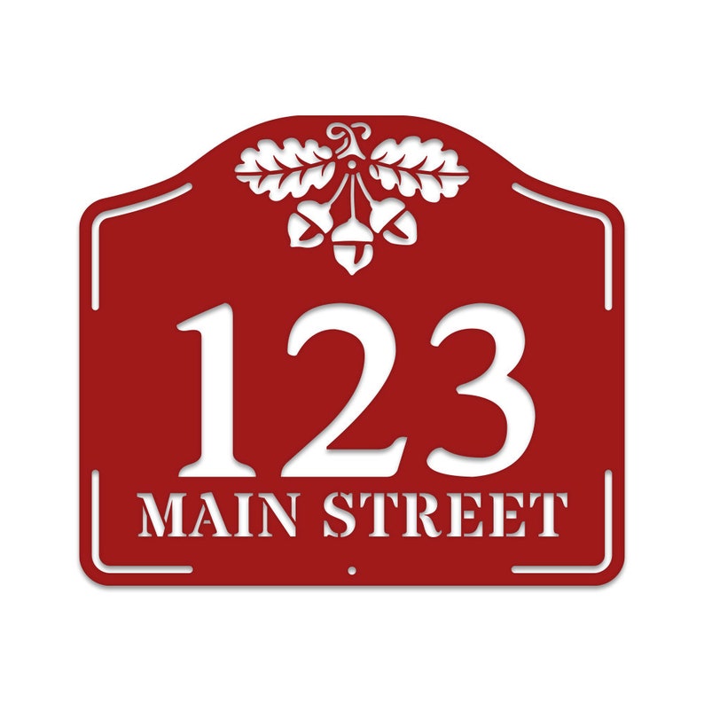 May include: Red metal house number sign with white lettering. The sign features the number 123 and the street name "MAIN STREET" with an acorn and oak leaf design at the top.