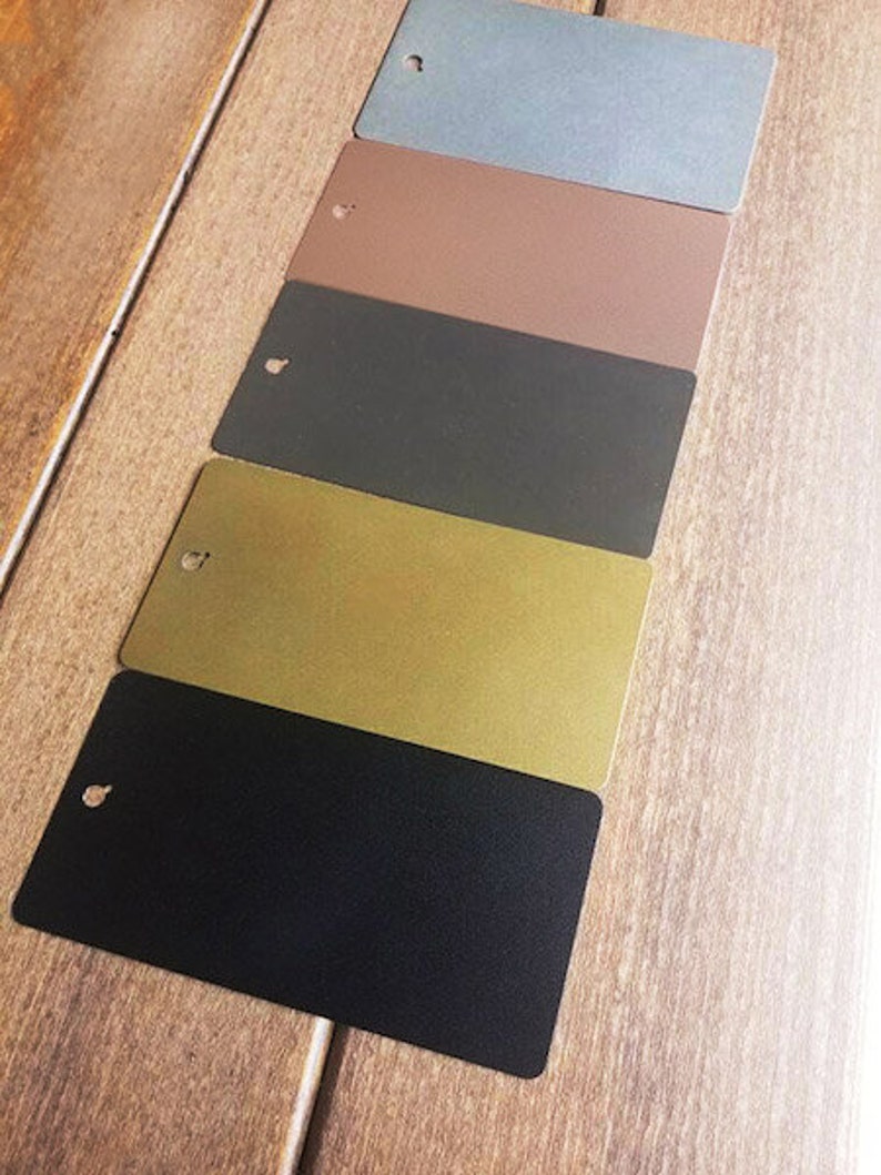 Pu&ograve; includere: Cinque campioni di colore di vernice su una superficie di legno. I colori sono blu chiaro, marrone, grigio scuro, oro e nero.