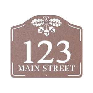 May include: A brown metal house number sign with an acorn and oak leaf design. The number 123 and the text "MAIN STREET" are cut out in white.
