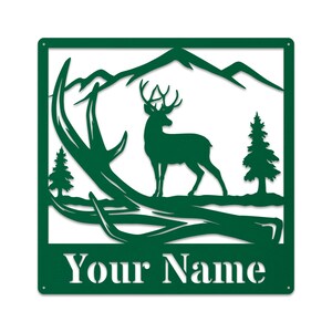 May include: Green metal sign with a silhouette of a deer standing in front of a mountain range with antlers in the foreground. The text "Your Name" is at the bottom of the sign.