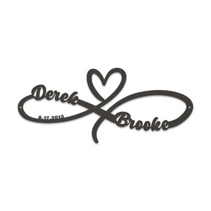 May include: Black metal infinity symbol with a heart in the centre. The names Derek and Brooke are written on either side of the heart, with the date 8.17.2013 below Derek's name.