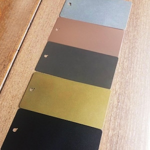 May include: Five metal samples in different colors, arranged in a row from top to bottom: light blue, brown, dark gray, gold, and black.