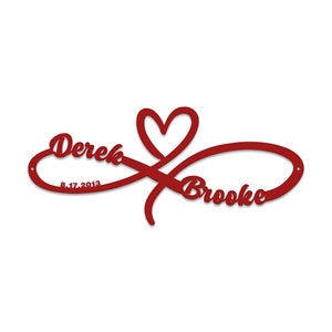 May include: Red metal infinity symbol with a heart in the centre. The names Derek and Brooke are written on either side of the heart, with the date 8.17.2013 below Derek's name.