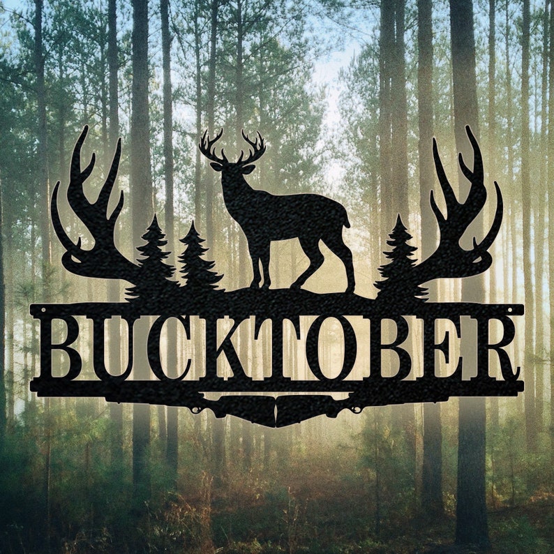 May include: Black metal sign with a silhouette of a buck deer with antlers and two pine trees. The sign says "BUCKTOBER" in large, bold letters.