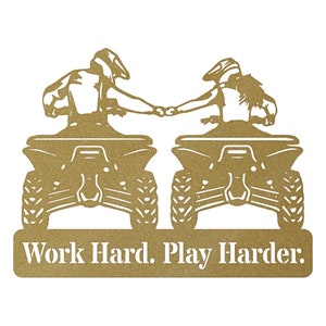 May include: A gold metal silhouette of two people riding quad bikes side-by-side, holding hands. The text "Work Hard. Play Harder." is below the image.