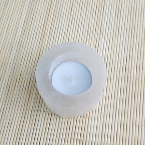 Pu&ograve; includere: Un portacandele di sale bianco di forma rotonda con una piccola candela tealight bianca all'interno.