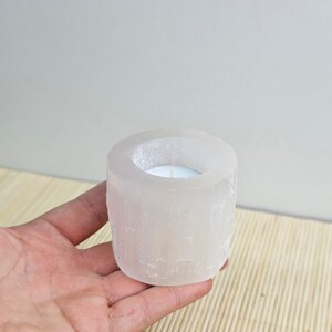 Pu&ograve; includere: Portacandele in selenite bianca con una piccola candela da t&egrave; bianca all'interno. Il portacandele &egrave; realizzato in cristallo di selenite naturale e ha una superficie ruvida e testurizzata.