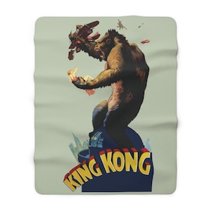 May include: A vintage poster for the movie "King Kong" featuring a large, brown gorilla holding a woman in one hand and a plane in the other. The gorilla is standing on a building with the city skyline in the background. The text "King Kong" is written in large, bold letters across the bottom of the poster.