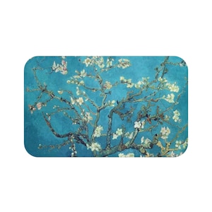 Può includere: Un dipinto di un mandorlo in fiore con fiori bianchi su uno sfondo blu. I rami dell'albero sono rappresentati in modo stilizzato, quasi astratto, con linee spesse e scure. Il dipinto ricorda lo stile di Vincent van Gogh.