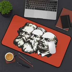 May include: A red mousepad with a black and white image of three men with beards. The men are arranged in a row, with the man on the left being the largest and the man on the right being the smallest. The men are all looking to the right.