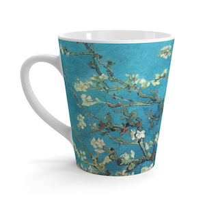 May include: White ceramic latte mug with a blue background and a painting of a blooming almond tree branch with white flowers. The painting is in the style of Vincent van Gogh.
