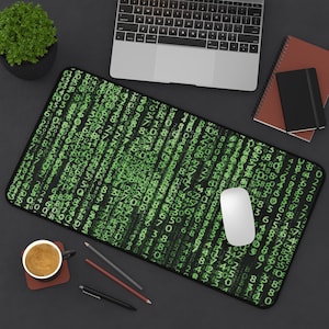 Op de afbeelding: Een zwarte en groene muismat met een herhalend patroon van groene cijfers op een zwarte achtergrond. Een witte computermuis ligt op de mat.