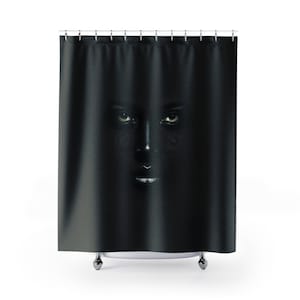 May include: A black shower curtain with a woman's face peeking out from behind the curtain. The woman's face is painted black with white eyes and lips.