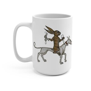 May include: A white ceramic mug with a brown rabbit riding a white dog. The rabbit is holding a small, curled object in its right hand. The dog has a red collar with a bell.