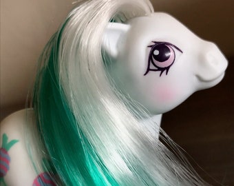 May include: A white pony with teal and white hair. The pony has candy cane designs on its body.