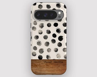 Op de afbeelding: Een telefoonhoesje met een crèmekleurige achtergrond en een patroon van zwarte stippen. Het onderste gedeelte heeft een houtnerf ontwerp met de tekst "Your Name". De hoes heeft een camera-uitsparing.
