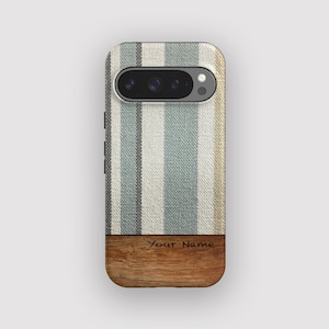 Peut inclure: Coque de téléphone à rayures bleues, blanches et beiges. La partie inférieure présente un motif imitation bois avec le texte "Your Name" gravé. Le boîtier a une découpe pour l'appareil photo et des boutons latéraux.