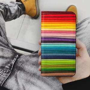 Pode incluir: Uma capa de telefone colorida com um padr&atilde;o de listras de arco-&iacute;ris. A capa &eacute; feita de um material dur&aacute;vel e &eacute; projetada para proteger seu telefone de arranh&otilde;es e impactos.
