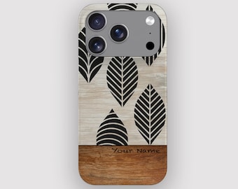 Puede incluir: Una funda de teléfono con un diseño de vetas de madera y patrones de hojas negras. La funda tiene un fondo claro de vetas de madera con hojas negras. La sección inferior es una veta de madera más oscura con el texto "Your Name".