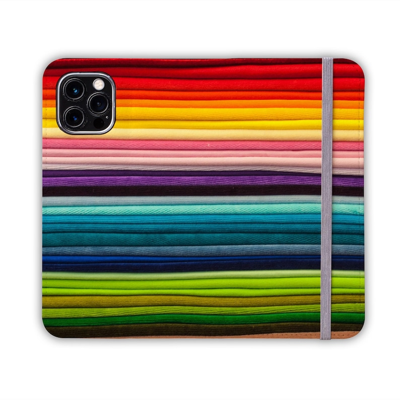 Pode incluir: Uma capa de telefone colorida com um padr&atilde;o de arco-&iacute;ris e um recorte para a c&acirc;mera. A capa tem uma banda el&aacute;stica cinza no lado direito.