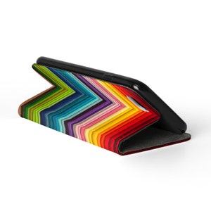Pode incluir: Uma capa de telefone preta com um padr&atilde;o de arco-&iacute;ris colorido. A capa &eacute; feita de um material dur&aacute;vel e tem uma aba que cobre a tela.