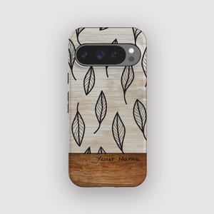 May include: A phone case featuring a wood grain base and a leaf pattern on a light wood-effect background. The case has a camera aperture and the text "Your Name" is visible on the wood grain.