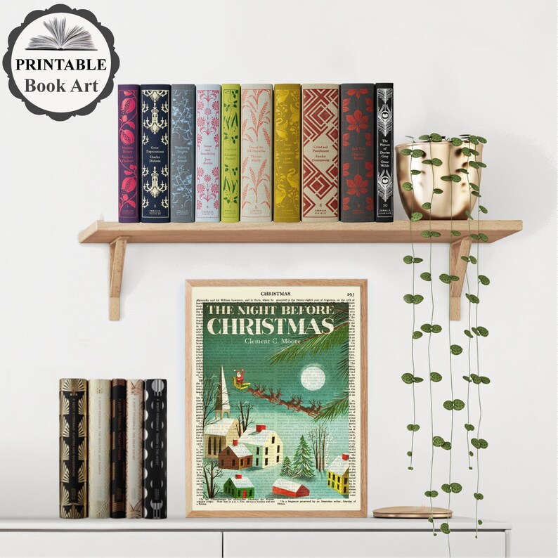 May include: A printable book art print featuring a vintage illustration of a snowy village scene with the text "The Night Before Christmas" and the author's name, Clement C. Moore. The print is framed and displayed on a shelf with a variety of books.