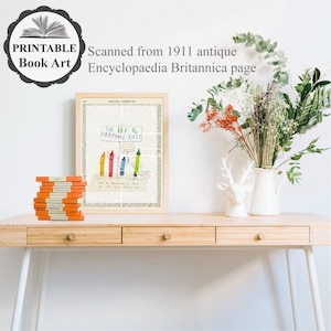 May include: A framed print featuring a vintage page from the 1911 Encyclopaedia Britannica, with a colorful crayon illustration and the text "THE DAY the CRAYONS QUIT." A stack of orange books sits to the left. A white vase with flowers is on the right.