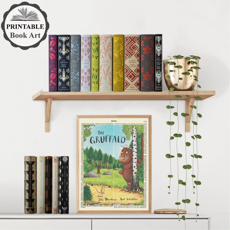 Pu&ograve; includere: Una stampa d'arte di libro stampabile del libro per bambini "Il Gruffalo" di Julia Donaldson e Axel Scheffler. La stampa presenta un'illustrazione colorata del Gruffalo, una creatura immaginaria con grandi orecchie, un naso lungo e macchie viola. La stampa &egrave; circondata da un bordo bianco ed &egrave; esposta su uno scaffale con una variet&agrave; di libri.