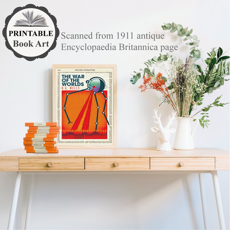 May include: A vintage book cover illustration of a Martian tripod from H.G. Wells' "The War of the Worlds" printed on a page from a 1911 edition of the Encyclopaedia Britannica. The illustration is framed and displayed on a wooden desk with a vase of dried flowers and a decorative deer statue.